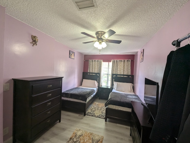 bedroom featuring ceiling fan, light hardwood / wood-style flooring, and a textured ceiling