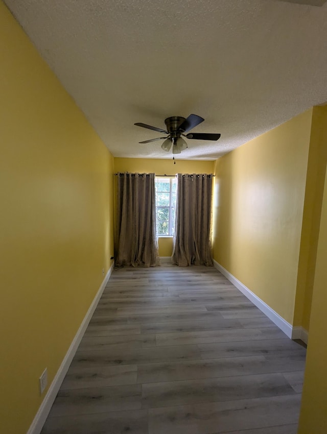 unfurnished room featuring ceiling fan, hardwood / wood-style floors, and a textured ceiling