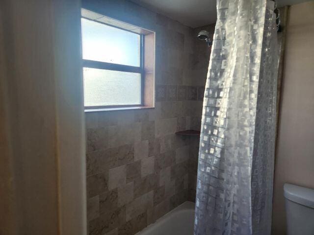 bathroom featuring shower / tub combo with curtain and toilet