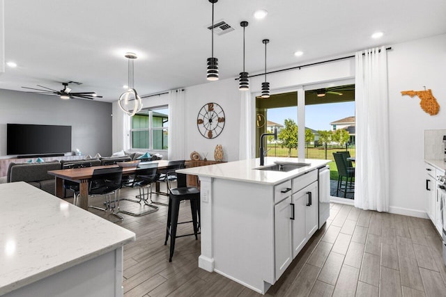 kitchen featuring a kitchen island with sink, ceiling fan, decorative light fixtures, and white cabinets