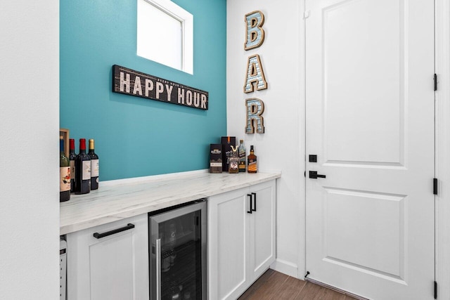 bar featuring wine cooler, dark hardwood / wood-style flooring, light stone countertops, and white cabinets