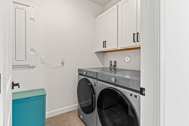 laundry room featuring washing machine and dryer, cabinets, and electric panel