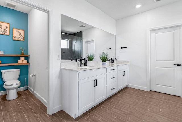 bathroom featuring vanity, a shower with shower door, and toilet