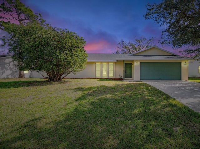 ranch-style house with a garage and a lawn