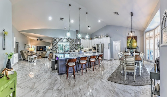 kitchen featuring white cabinets, ceiling fan, decorative light fixtures, vaulted ceiling, and a breakfast bar