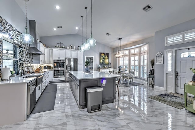 kitchen with pendant lighting, white cabinets, high vaulted ceiling, a breakfast bar area, and a kitchen island with sink