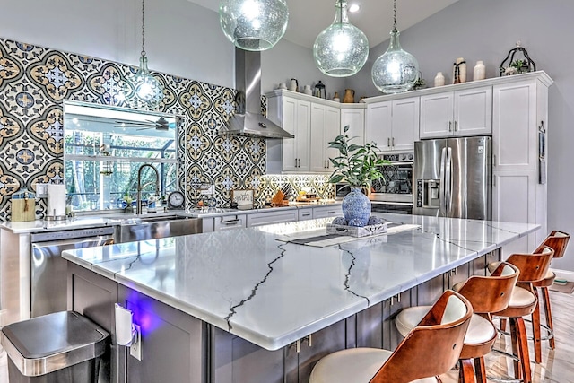 kitchen with a kitchen island, wall chimney exhaust hood, stainless steel appliances, and white cabinetry