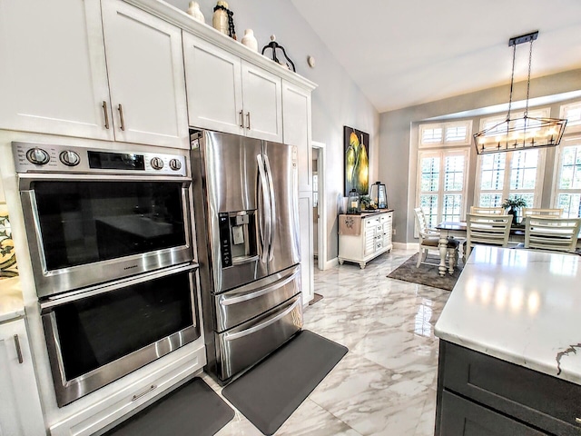 kitchen with appliances with stainless steel finishes, an inviting chandelier, lofted ceiling, pendant lighting, and white cabinets