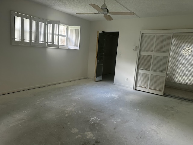 unfurnished bedroom featuring ceiling fan, concrete floors, baseboards, and a textured ceiling