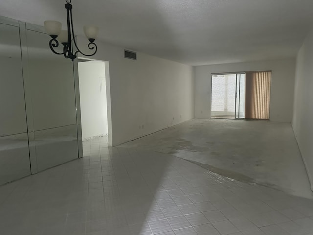 unfurnished room featuring visible vents and an inviting chandelier