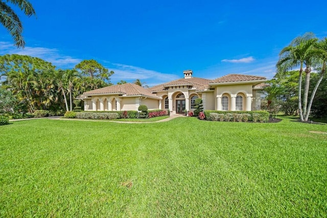 mediterranean / spanish home with a tiled roof, a front lawn, and stucco siding