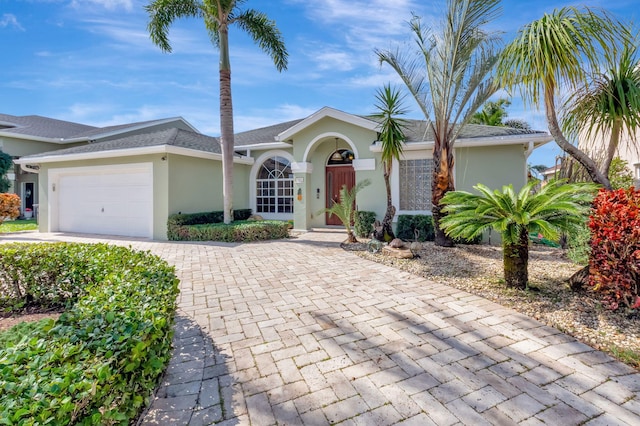 ranch-style house with decorative driveway, an attached garage, and stucco siding