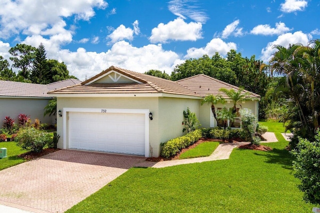 single story home featuring a front lawn, a tile roof, stucco siding, decorative driveway, and an attached garage