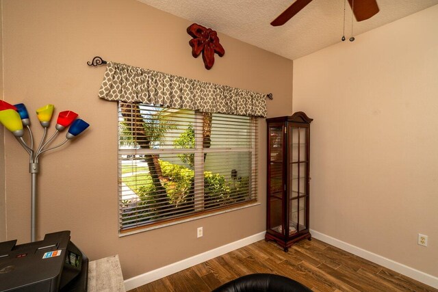 interior space with ceiling fan, baseboards, a textured ceiling, and wood finished floors