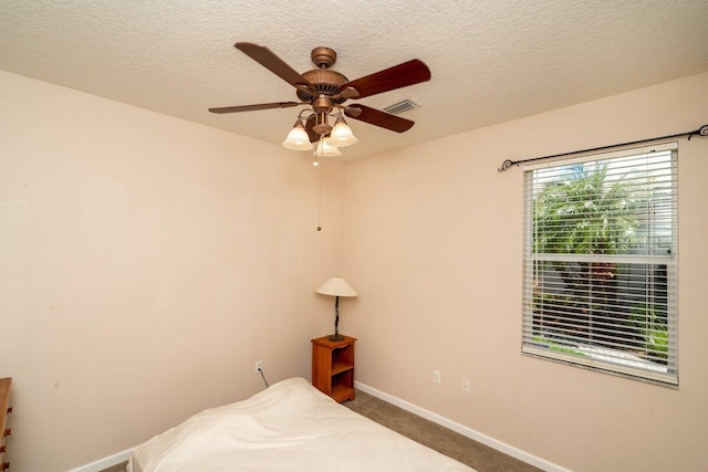 carpeted bedroom featuring visible vents, baseboards, a textured ceiling, and ceiling fan