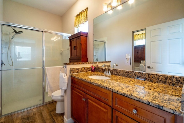 bathroom featuring vanity, a shower stall, toilet, and wood finished floors