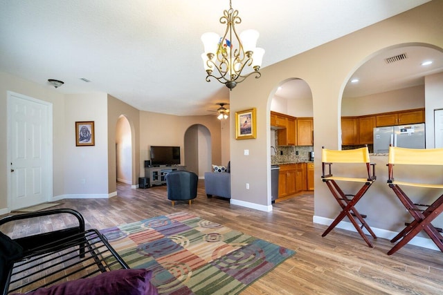 living room featuring visible vents, light wood-style floors, arched walkways, and baseboards