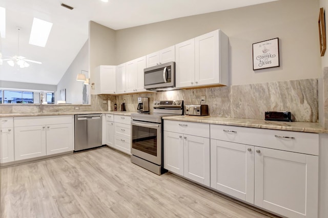 kitchen featuring decorative backsplash, appliances with stainless steel finishes, white cabinets, and a sink