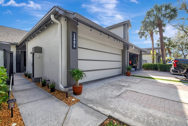 view of side of home featuring a garage, driveway, and stucco siding