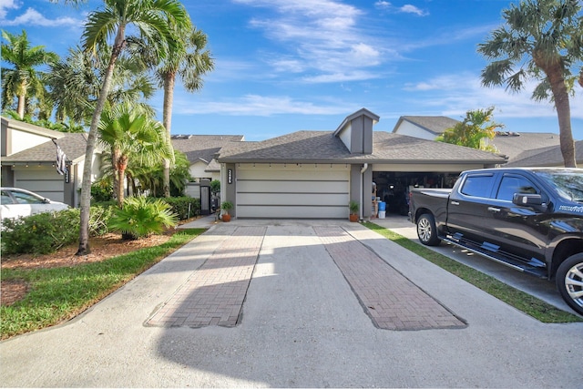 view of front facade with an attached garage, a shingled roof, concrete driveway, and stucco siding