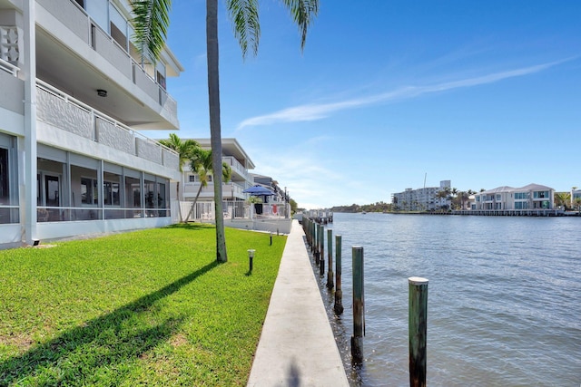 view of dock with a water view and a yard