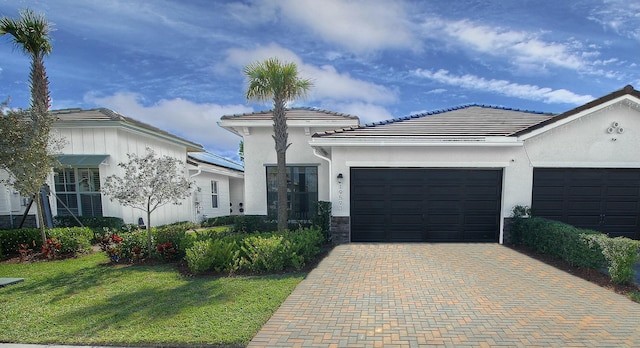 view of front facade featuring a front yard, decorative driveway, an attached garage, and stucco siding