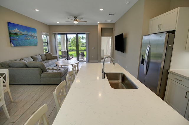 kitchen featuring a sink, visible vents, light wood-style floors, open floor plan, and stainless steel fridge