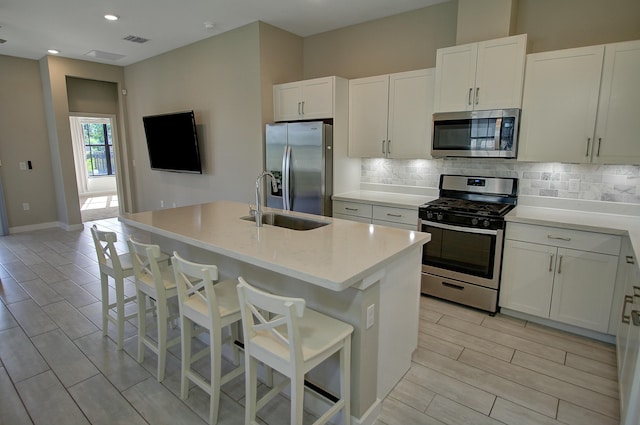 kitchen featuring a sink, white cabinetry, light countertops, appliances with stainless steel finishes, and tasteful backsplash