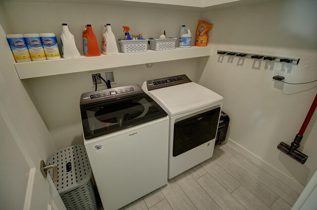 laundry room featuring wood finish floors, laundry area, baseboards, and washing machine and clothes dryer