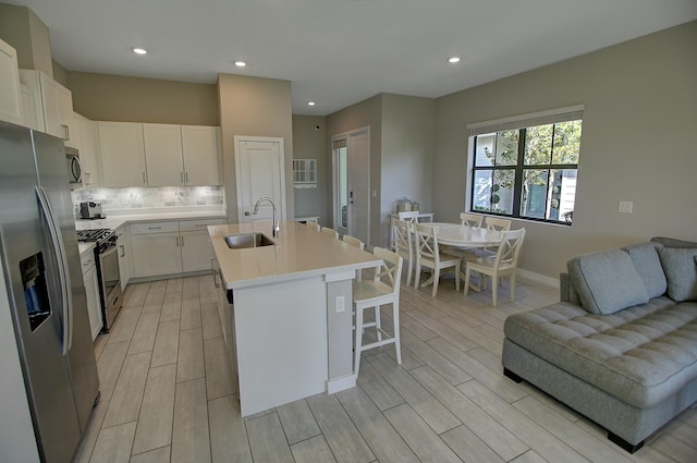 kitchen with tasteful backsplash, stainless steel appliances, a sink, and wood finish floors