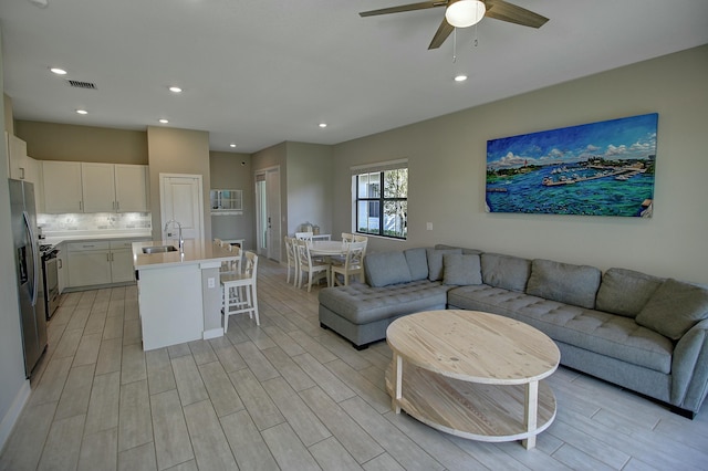 living area with a ceiling fan, wood finish floors, visible vents, and recessed lighting