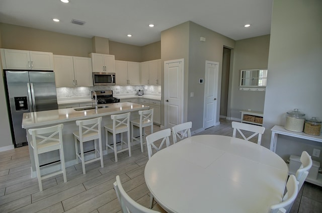 kitchen featuring appliances with stainless steel finishes, wood tiled floor, light countertops, and decorative backsplash