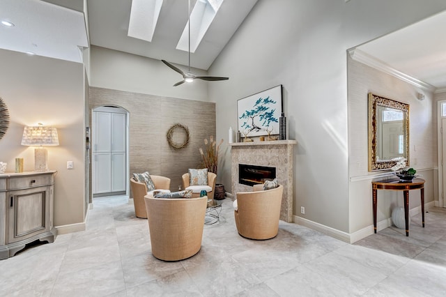 sitting room featuring ornamental molding, a skylight, high vaulted ceiling, and ceiling fan