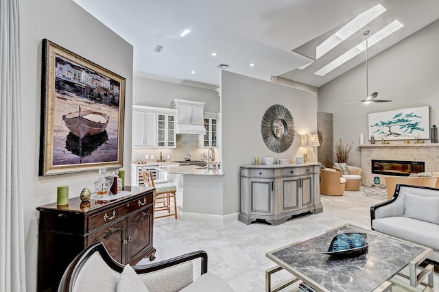 living room with a skylight, high vaulted ceiling, and ceiling fan