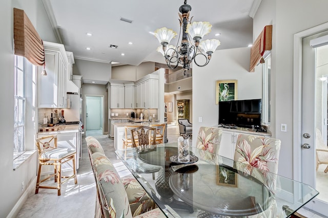 dining room featuring an inviting chandelier, sink, and crown molding