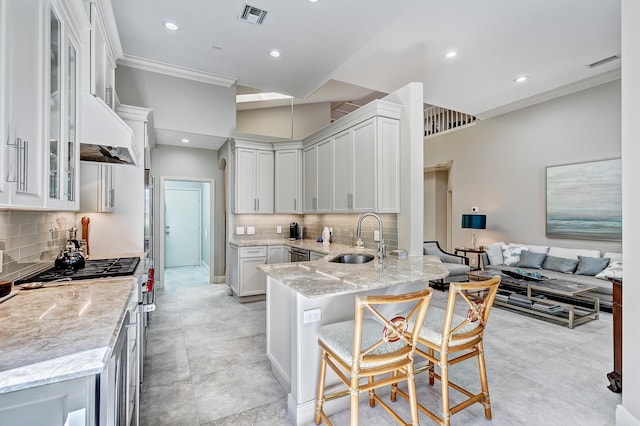 kitchen featuring a breakfast bar, white cabinetry, sink, high end range, and light stone countertops