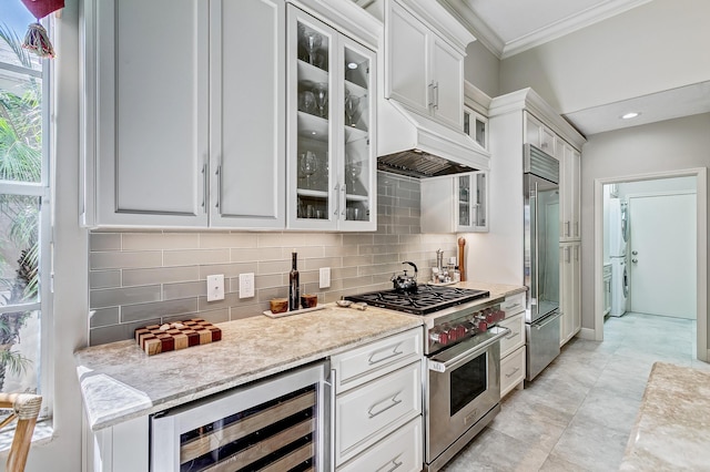 kitchen with wine cooler, white cabinetry, crown molding, high end appliances, and tasteful backsplash