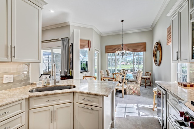 kitchen featuring sink, wine cooler, ornamental molding, light stone countertops, and decorative light fixtures