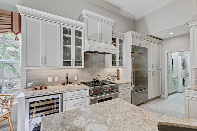 kitchen featuring stacked washer / dryer, white cabinets, wine cooler, and premium appliances