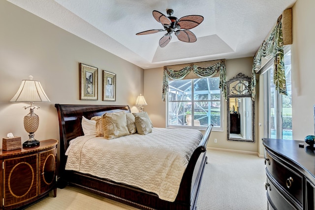 carpeted bedroom featuring ceiling fan, a tray ceiling, and a textured ceiling