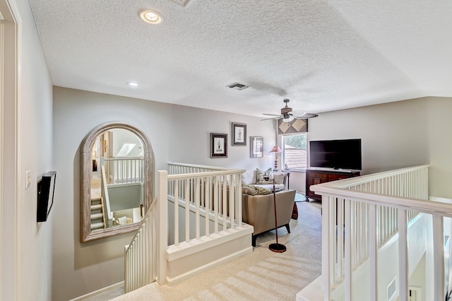 bedroom featuring ceiling fan, light carpet, and a textured ceiling