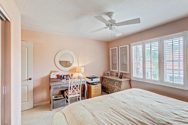 bedroom with ceiling fan, light colored carpet, and a textured ceiling