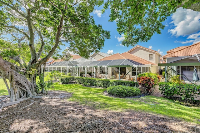 rear view of property featuring a lawn and glass enclosure