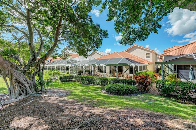 rear view of property with a yard and glass enclosure