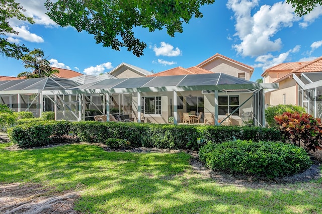 rear view of house with a lanai, a lawn, and a patio area