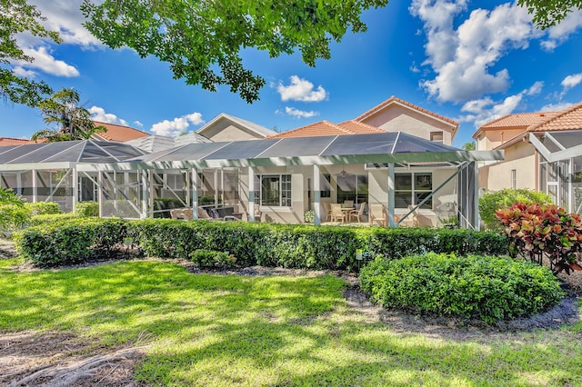 rear view of property featuring a lanai, a patio area, and a lawn