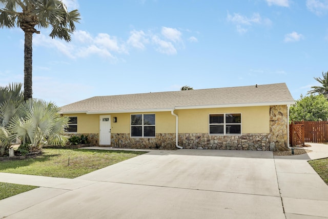 ranch-style house featuring stone siding, a front yard, fence, and stucco siding