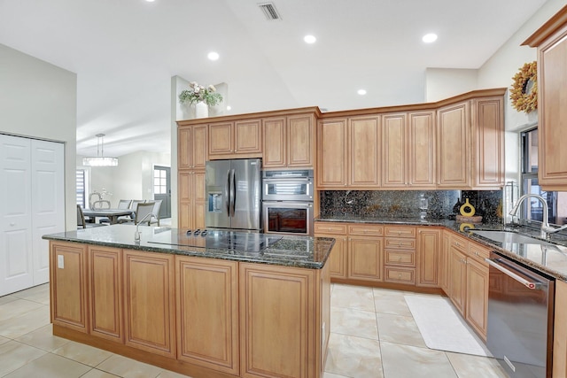 kitchen with stainless steel appliances, sink, a kitchen island, and dark stone countertops