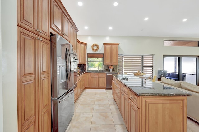 kitchen with sink, tasteful backsplash, light tile patterned floors, dark stone countertops, and stainless steel appliances