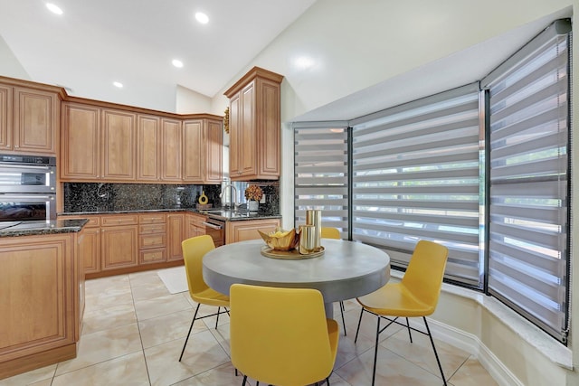 kitchen featuring sink, light tile patterned floors, double oven, and decorative backsplash